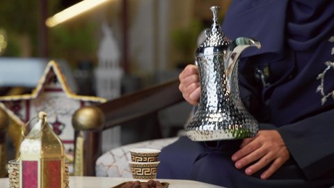 صب القهوه العربيه، حسن الاستقبال وكرم الضيافة في شهر رمضان، جلسة ليلية خارجية في إحدى شاليهات الامارات، الاستمتاع بشرب المشروبات الساخنه ، صديقتان عربيتان خليجيتان اماراتيان ترتديان العباءة والحجاب تجلسان في الهواء الطلق يتبادلان الاحاديث والاخبار بتعابير السرور،  قضاء وقت ممتع مع الأصدقاء