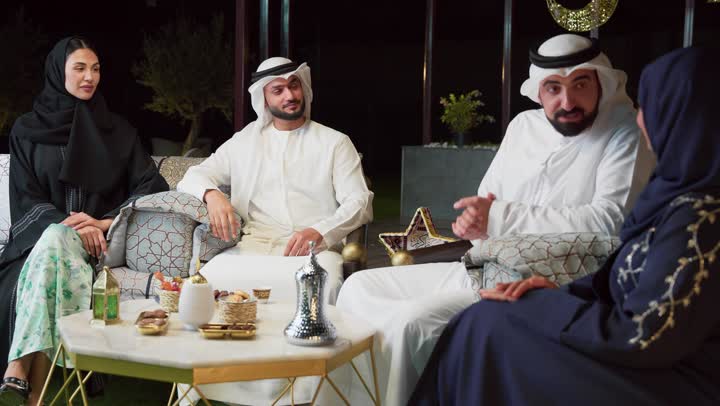 عائله عربيه خليجيه اماراتيه تجلس في شاليه سياحي يقومون بتبادل الاحاديث بتعابير السرور، حسن الاستقبال وكرم الضيافة في شهر رمضان المبارك، الاستمتاع بتناول المشروبات الباردة ، زينة وديكور رمضاني، قضاء وقت ممتع مع العائله في الهواء الطلق