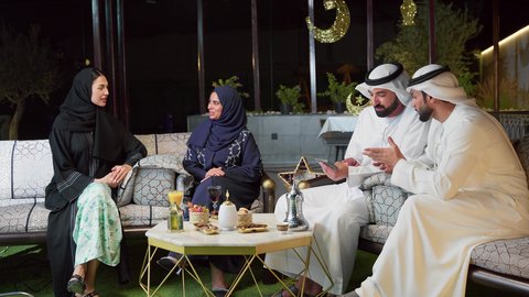 الاستمتاع بتناول المشروبات الباردة ، زينة وديكور رمضاني، قضاء وقت ممتع مع العائله في الهواء الطلق، حسن الاستقبال وكرم الضيافة في شهر رمضان المبارك، عائله عربيه خليجيه اماراتيه تجلس في شاليه سياحي يقومون بتبادل الاحاديث بتعابير السرور