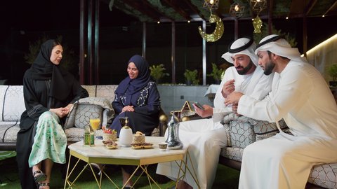 قضاء وقت ممتع مع العائله في الهواء الطلق، زينة وديكور رمضاني، حسن الاستقبال وكرم الضيافة في شهر رمضان المبارك، عائله عربيه خليجيه اماراتيه تجلس في شاليه سياحي يقومون بتبادل الاحاديث بتعابير السرور، الاستمتاع بتناول المشروبات الباردة