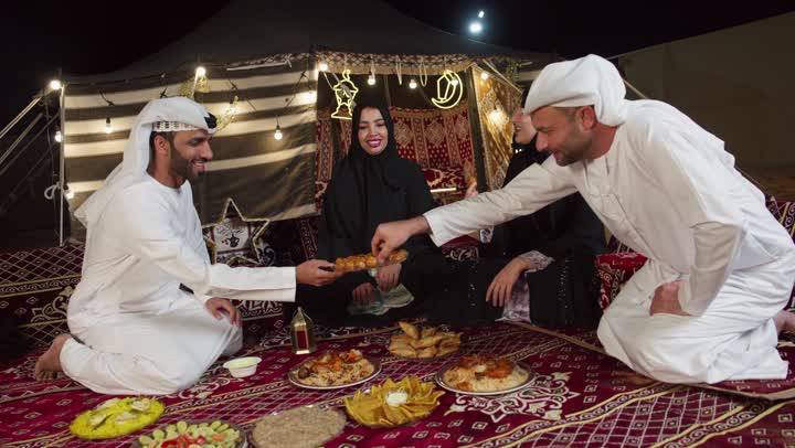 كرم الضيف وحسن الاستقبال، تبادل المأكولات والمقبلات بين الاصدقاء، التجمع حول مائده الافطار في شهر رمضان، اصدقاء اماراتيون يجلسون في خيمه بدويه شعبيه يقومون بتقديم المقبلات والحلوي، المجلس الشعبي التقليدي، التخيم الليلي في الصحراء