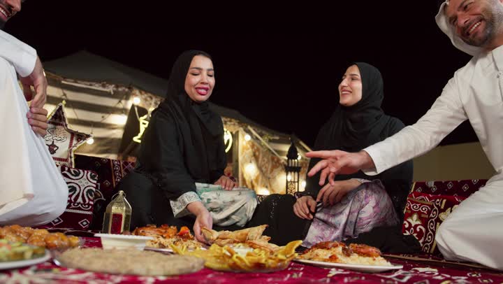 ايماءه يدين تدل علي الاشاره لشئ ما، افطار عائلي في خيمه وسط الصحراء، عائله اماراتيه تستمتع بتناول المقبلات الشهيه، التخييم في اجواء شهر رمضان الكريم، كشته وجلسه برشبابيه، ديكورات وزينه شهر رمضان، كرم الضيافه وحسن الاستقبال