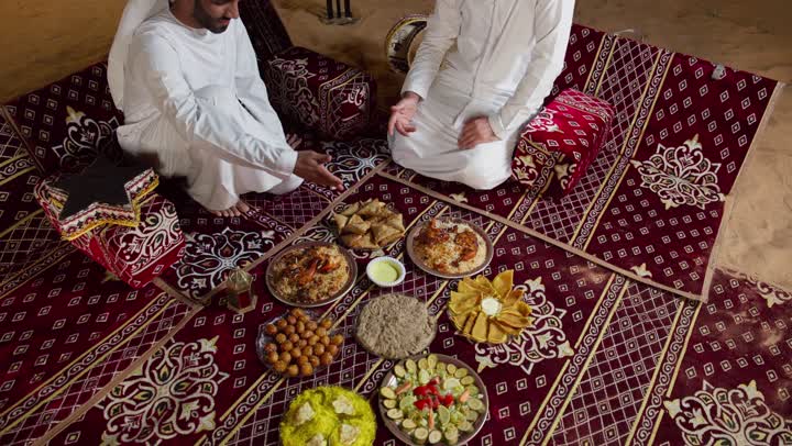 شابان عربيان خليجيان اماراتيان يجلسان على المائدة، أطباق شعبيه عربيه اماراتيه خليجيه، صحن من الأرز مع الدجاج، اصول المجلس الشعبي، طبق من أرز المندي اللذيذ، رجلان اماراتيان يتناولان الارز الشعبي بالايد، اصول تناول الطعام باليد