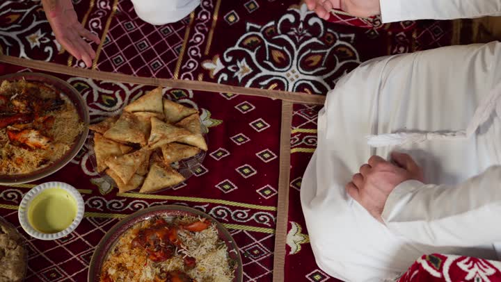 شابان عربيان خليجيان اماراتيان يجلسان على المائدة، أطباق شعبيه عربيه اماراتيه خليجيه، صحن من الأرز مع الدجاج، اصول المجلس الشعبي، طبق من أرز المندي اللذيذ، رجلان اماراتيان يتناولان الارز الشعبي بالايد، اصول تناول الطعام باليد