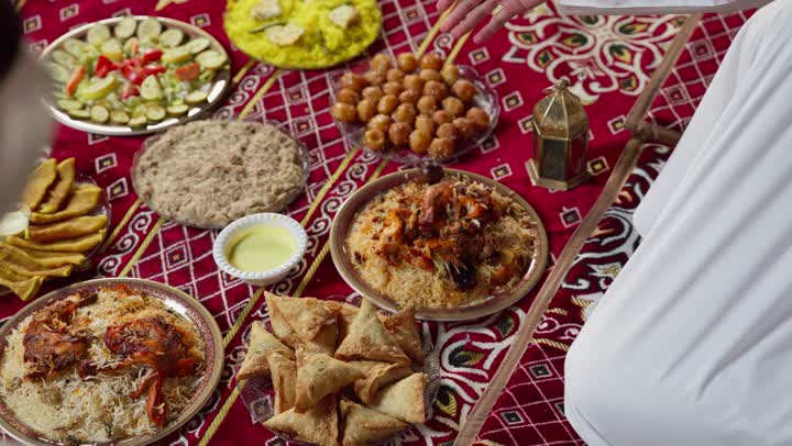 اصول تناول الطعام باليد، تصوير مقربة ليدين شابان عربيان خليجيان سعوديان يجلسان على المائدة، أطباق شعبيه عربيه سعوديه خليجيه، صحن من الأرز مع الدجاج، اصول المجلس الشعبي، طبق من أرز المندي اللذيذ، رجلان اماراتيان يتناولان الارز الشعبي بالايد