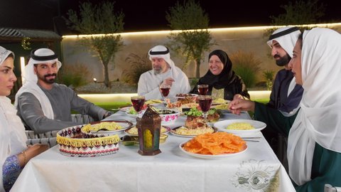 الاستمتاع بقضاء وقت الإفطار مع الأسرة، نقاش وحوار عائلي، مائده طعام مليئه بأصناف المأكولات و المقبلات الشهية، تجمع أسرة عربية خليجية اماراتية حول سفرة الإفطار في شهر رمضان المبارك، طفل خليجي يمسك الفانوس بايماءات السعاده و السرور