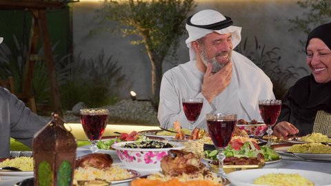 ديكور وأجواء رمضانية، نقاش وحوار عائلي، مائده طعام مليئه بأصناف المأكولات و المقبلات الشهية، تجمع أسرة عربية خليجية اماراتية حول سفرة الإفطار في شهر رمضان المبارك، طفل خليجي يمسك الفانوس بايماءات السعاده و السرور