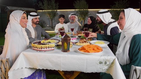 الاستمتاع بتناول المشروبات الرمضانية، نقاش وحوار عائلي، مائده طعام مليئه بأصناف المأكولات و المقبلات الشهية، ديكور وأجواء رمضانية، تصويرلتجمع أسرة عربية خليجية اماراتية حول سفرة الإفطار في شهر رمضان المبارك، ايماءات السعادة والسرور