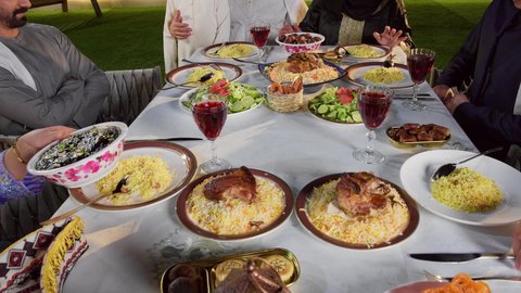 مائده طعام مليئه بأصناف المأكولات و المقبلات الشهية، ديكور وأجواء رمضانية، نقاش وحوار عائلي، تجمع أسرة عربية خليجية اماراتية حول سفرة الإفطار في شهر رمضان المبارك، ايماءات السعادة والسرور، حسن الضيافة و الاكرام