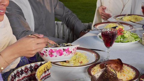 جلسة عائلية مليئة بالمحبة والاحترام، الكرم والمشاركة خلال وقت الإفطار, أجواء رمضانية روحانية، تصوير مقرب لامراه عربيه خليجيه اماراتية تقوم بغرف طبق من الورق عنب، تجمع العائلة على سفرة الاكل، الاحتفال بالاعياد و المناسبات الاسلامية