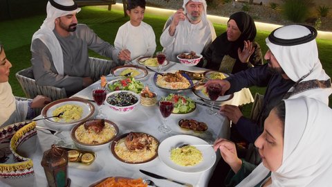 المناسبات الاسلامية و الدينية، اجواء رمضانية روحانية، تقديم المأكولات على مائدة الإفطار, تصوير لعائله عربيه خليجيه اماراتية تقوم بتناول الافطار الجماعي، رجل عربيى خليجي يقوم بتناول طبق من التمر, أجواء شهر رمضان المبارك في الامارات
