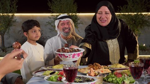 اجواء رمضانية روحانية، تقديم المأكولات على مائدة الإفطار,تصوير مقرب لامرأة عربية خليجية اماراتية مبتسمه تقوم بتقديم طبق من التمر , أجواء شهر رمضان المبارك في الامارات, المناسبات الاسلامية و الدينية