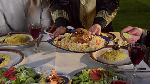 قضاء أوقات ممتعه مع العائله في الخارج، أسرة عربيه خليجيه اماراتية تقوم بتناول الطعام العائلي في أحد المطاعم، كسر الصيام عند سماع أذان المغرب، مائده إفطار مليئه بالأصناف والمأكولات الشهية، تصوير مقرب ليد امراة عربية خليجيه تقوم بتقديم طبق من الارز