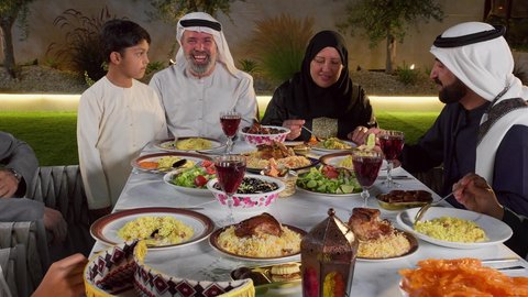 مائده طعام مليئه بأصناف المأكولات و المقبلات الشهية، ديكور وأجواء رمضانية، نقاش وحوار عائلي، تجمع أسرة عربية خليجية اماراتية حول سفرة الإفطار في شهر رمضان المبارك، ايماءات السعادة والسرور، حسن الضيافة و الاكرام
