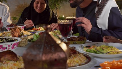 مشاركة الأطعمة و إكرام الضيف، أجواء دينية رمضانية، أداء فريضة الصيام، العزائم والولائم في الأعياد والمناسبات الإسلامية، تصوير مقرب لرجل عربي خليجي اماراتي يرتدي الزي التقليدي يقوم بتقديم طبق من التمر، ايماءات السعادة و السرور