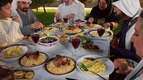 مائده طعام مليئه بأصناف المأكولات و المقبلات الشهية، ديكور وأجواء رمضانية، نقاش وحوار عائلي، تجمع أسرة عربية خليجية اماراتية حول سفرة الإفطار في شهر رمضان المبارك، ايماءات السعادة والسرور، حسن الضيافة و الاكرام