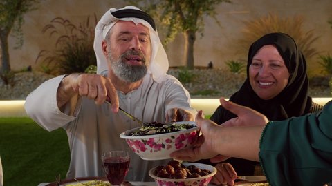 أجواء دينية رمضانية، تصويرمقرب لرجل عربي خليجي اماراتي يرتدي الزي التقليدي يقوم بتناول طبق من الورق عنب، أداء فريضة الصيام، ايماءات السعاده و السرور