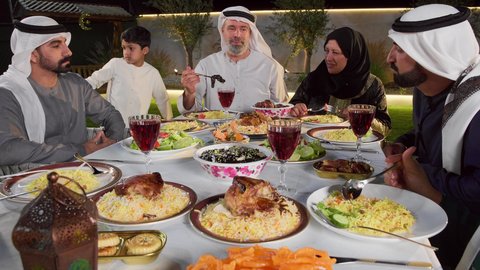 مائده طعام مليئه بأصناف المأكولات و المقبلات الشهية، ديكور وأجواء رمضانية، نقاش وحوار عائلي، تجمع أسرة عربية خليجية اماراتية حول سفرة الإفطار في شهر رمضان المبارك، ايماءات السعادة والسرور، حسن الضيافة و الاكرام