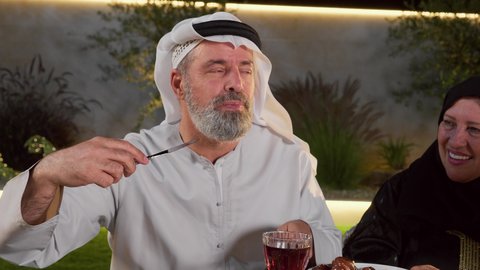 أجواء دينية رمضانية، تصويرمقرب لرجل عربي خليجي اماراتي يرتدي الزي التقليدي  يقوم بتناول الافطارالشهي، أداء فريضة الصيام، ايماءات السعاده و السرور