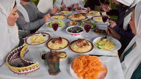 مائده طعام مليئه بأصناف المأكولات و المقبلات الشهية، ديكور وأجواء رمضانية، نقاش وحوار عائلي، تصوير مقرب لتجمع أسرة عربية خليجية اماراتية حول سفرة الإفطار في شهر رمضان المبارك، ايماءات السعادة والسرور