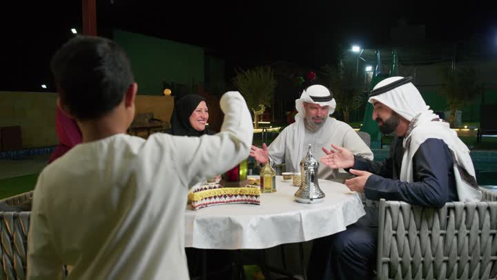 سهرات عائلية وأجواء رمضانية، طفل عربي خليجي اماراتي يمسك بيده فانوس معدني، استخدام الديكورات الفنية في الزينة، جلسة أسرية في حديقة المنزل، التمتع بالهواء الطلق، عائله اماراتيه تجلس في احد الاماكن الخارجيه، التسامر مع افراد العائله