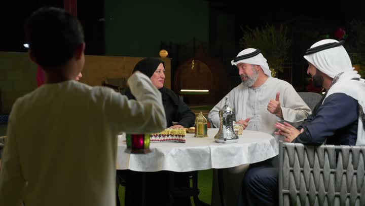 سهرات عائلية وأجواء رمضانية، طفل عربي خليجي اماراتي يمسك بيده فانوس معدني، استخدام الديكورات الفنية في الزينة، جلسة أسرية في حديقة المنزل، التمتع بالهواء الطلق، عائله اماراتيه تجلس في احد الاماكن الخارجيه، التسامر مع افراد العائله