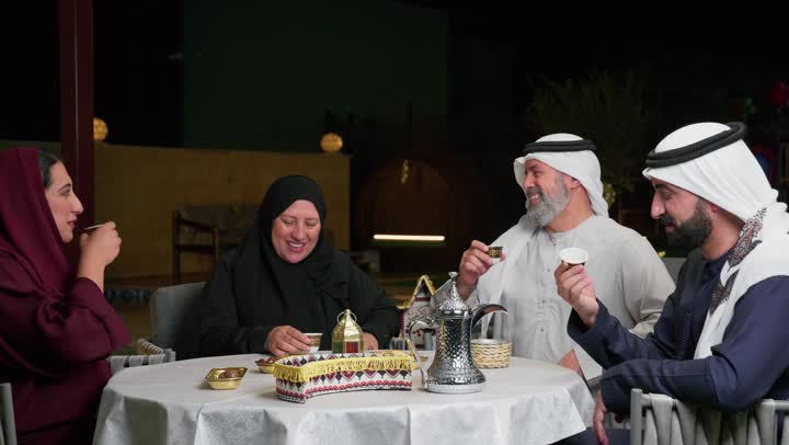 الاستمتاع بشرب القهوه مع العائلة,  عائلة عربية خليجية اماراتيه مجتمعة على طاولة الطعام, اجواء وروحانيات شهر رمضان المبارك, ايماءات السعادة بقدوم الشهر الفضيل, احترام العائله وكبار السن، ديكورات وزينه رمضانيه علي الطاوله، تمور ومقبلات للافطار