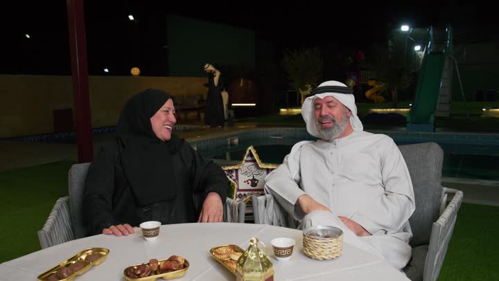 زيارات وتجمعات عائليه، كرم الضيافة وحسن الاستقبال، العادات والتقاليد في الامارات العربية المتحدة، رجل مسن عربي خليجي اماراتي يرتدي الكندوره برفقه زوجته وعائلته، ديكورات وزينه رمضان المبارك علي الطاوله