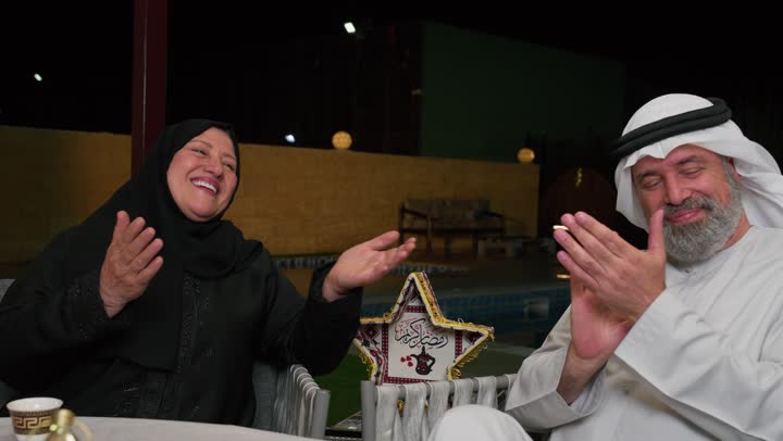 الضحك والتسامروتبادل الأحاديث بين أفراد الأسرة، أجواء عائلية دينية رمضانية سعيدة، فوانيس معدنية مزخرفة ملونة على سفرة الطعام، زينة المناسبات الإسلامية، أداء فريضة الصيام في شهر رمضان المبارك، عائلة عربية خليجية اماراتيه مجتمعة حول مائدة الطعام