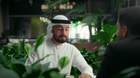 اجتماع الرفاق في إحدى المقاهي الإماراتية الراقية، جلسة وناسة في عطلة نهاية الاسبوع، قضاء وقت ممتع برفقة الأصدقاء، تصوير مقرب لصديقين عربيين خليجيين إماراتيين يجلسان في مقهى يقومان بتبادل أطراف الحديث بإيماءات السعادة والسرور، الاستمتاع بالأجواء الهادئة في الخارج