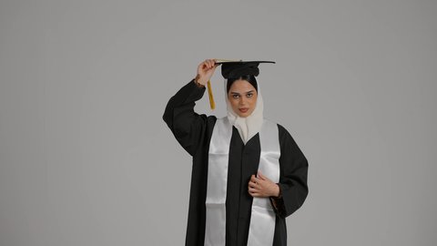 الاهتمام بالأناقة والمظهر الخارجي، إيماءات الفرح والسرور، الاحتفال بالتخرج من الجامعة، الشعور بالفخر والثقه بالنفس ، تحقيق حلم النجاح, إنهاء الدراسة الجامعية، مفهوم الاجتهاد والتفوق ، تصوير مقرب لطالبة عربية خليجية اماراتيه محجبة ترتدي روب التخرج ، ترفع قبعه التخرج بايديها