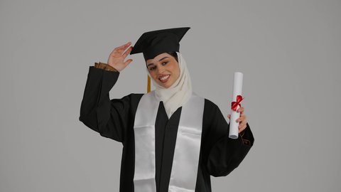 تحقيق حلم النجاح ، الشعور بالثقة بالنفس والفخر، جودة التعليم في المملكة ، إنهاء الدراسة الجامعية ، الاحتفالات والمناسبات الجامعية, مفهوم الاجتهاد والتفوق،تصوير مقرب لطالبة عربية خليجية اماراتيه محجبة ترتدي روب التخرج ، تحمل بيدها وثيقه النجاح وقبعة التخرج