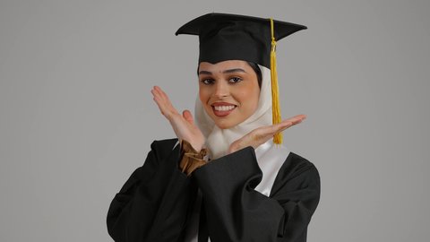 الاهتمام بالاناقه والمظهر الخارجى ، جودة التعليم في المملكة ، الاحتفالات والمناسبات الجامعية, مفهوم الاجتهاد والتفوق، الشعور بالثقة بالنفس والفخر، تصوير مقرب لطالبة عربية خليجية اماراتيه محجبة ترتدي روب وقبعة التخرج ووثيقه النجاح، تضع وشاح علم الامارات على كتفها، إنهاء الدراسة الجامعية