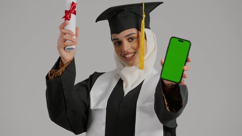 Integrating technology into daily life, university celebrations and events, the concept of diligence and excellence, a sense of self-confidence and pride, a close-up of a veiled Emirati Gulf Arab student wearing a graduation gown and cap, holding a mobile phone and a success certificate, wearing a UAE flag scarf on her shoulder, completing university studies, quality of education in the Kingdom
