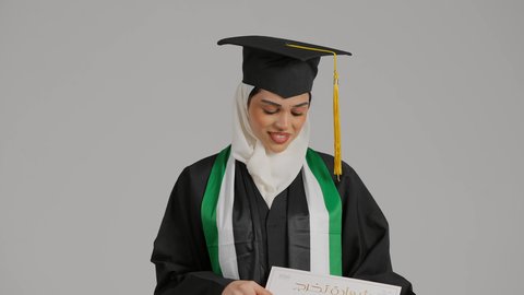 مفهوم الاجتهاد والتفوق، الشعور بالثقة بالنفس، عرض شهادة التخرج بايماءات الفخر ، تصوير مقرب لطالبة عربية خليجية اماراتيه محجبة ترتدي عباءه وقبعة التخرج ، تضع وشاح علم الامارات على كتفها، تحمل بيدها وثيقه النجاح، الاحتفالات والمناسبات الجامعية, إنهاء الدراسة الجامعية، جودة التعليم في المملكة