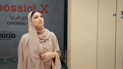 اقتناء نظارات حماية من الشمس،  مفهوم التبضع و شراء الاكسسورات ، مجموعه من نظارات الشمسية في محل خليجي، تصوير مقرب  لامراة عربيه خليجيه اماراتية ترتدي العباءه الملونه تقوم باختيار نظاره شمسيه من الارفف المعروضه، سيده سعوديه تقوم بالتسوق داخل المول