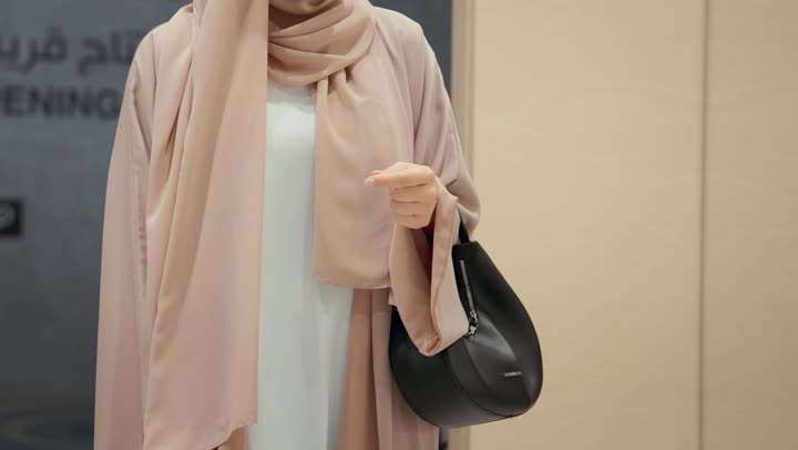 Buying sun glasses, a collection of sunglasses in a Gulf store, close-up of an Emirati Gulf Arab woman wearing a colorful abaya choosing sunglasses from the shelves, a Saudi woman shopping inside the mall