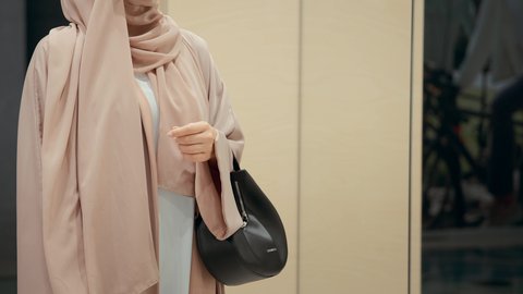 اقتناء نظارات حماية من الشمس، مجموعه من نظارات الشمسية في محل خليجي، تصوير مقرب  لامراة عربيه خليجيه اماراتية ترتدي العباءه الملونه تقوم باختيار نظاره شمسيه من الارفف المعروضه، سيده سعوديه تقوم بالتسوق داخل المول