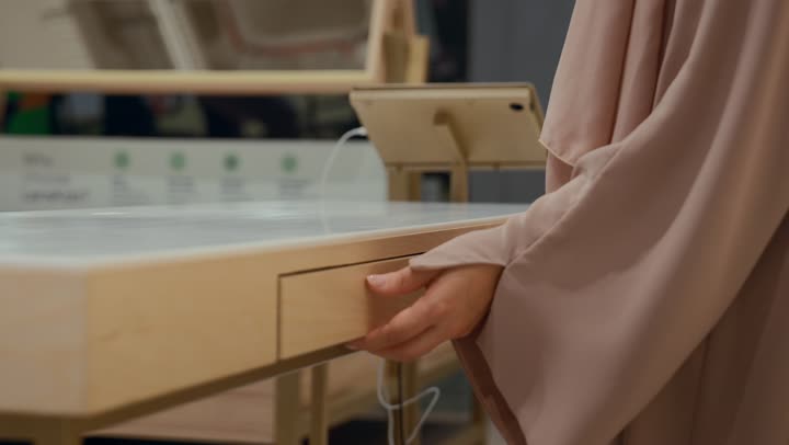 Buying sunglasses, a new wide range of eyeglasses in a Gulf store, how to choose sunglasses that suit your facial features, an Arab Gulf Emirati woman wearing a colorful abaya choosing sunglasses from inside the drawers