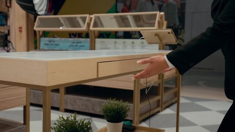 اقتناء نظارات حماية من الشمس، كيفية إختيار النظارة الشمسية الملائمة لملامح الوجه ، تصوير مقرب من الجانب لبائعه خليجيه تقوم بعرض النظارات الشمسيه الموجوده في الادراج المغقله، تشكيلة واسعة جديدة من نظارات النظر في محل خليجي