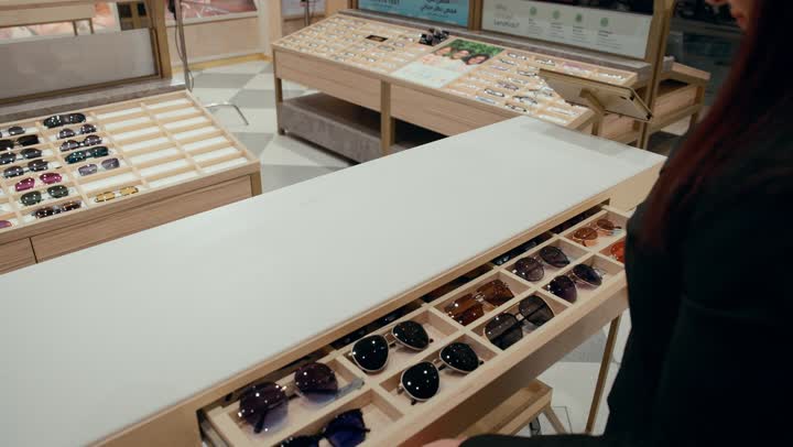 Buying sunglasses, how to choose sunglasses that suit your facial features, a close-up of a Gulf saleswoman displaying sunglasses in closed drawers, a new wide range of eyeglasses in a Gulf store