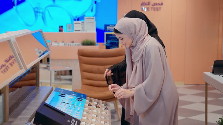 تشكيلة واسعة جديدة من نظارات النظر في محل خليجي ، امراة عربيه خليجيه اماراتية ترتدي العباءه الملونه تقوم باختيار نظارة نظر ، الاستمتاع بالتسوق في المول، بائعه خليجية تقوم بعرض مجموعه من اشكال النظارات