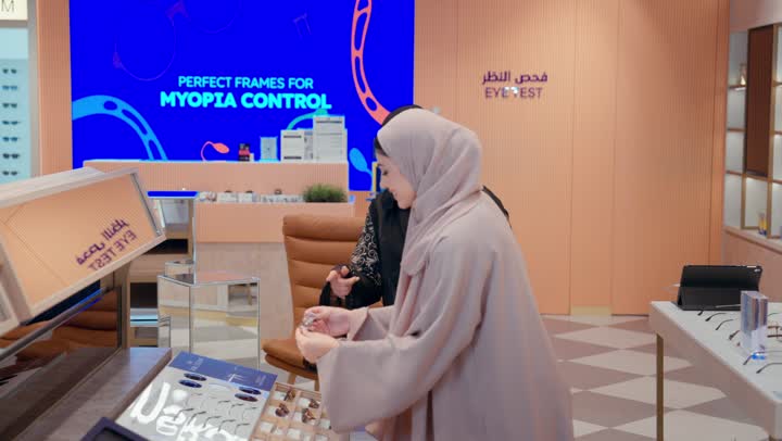 تشكيلة واسعة جديدة من نظارات النظر في محل خليجي ، امراة عربيه خليجيه اماراتية ترتدي العباءه الملونه تقوم باختيار نظارة نظر ، الاستمتاع بالتسوق في المول