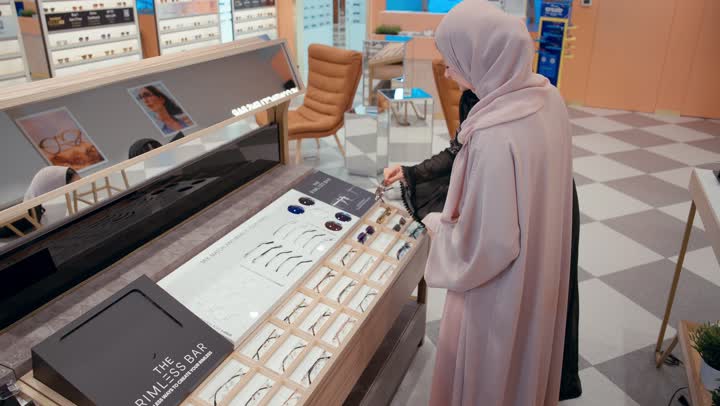Buying sunglasses, stylish sunglasses collection, sunglasses exhibition, Gulf saleswoman displaying a collection of glasses for an Emirati girl in an optical shop, an Arab Gulf Emirati woman wearing a black abaya choosing the appropriate look