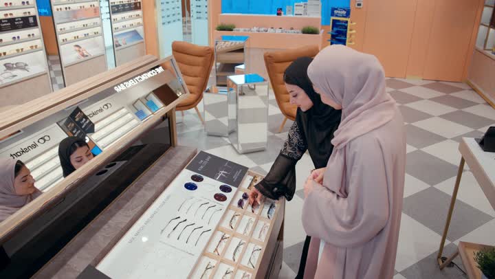 Stylish sunglasses collection, sunglasses exhibition, Gulf saleswoman displaying a collection of glasses for an Emirati girl in an eyewear store, purchasing sun protection glasses, an Arab Gulf Emirati woman wearing a black abaya choosing the appropriate look