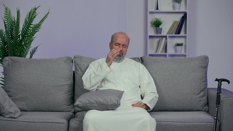 الشعور بالدوار وإيماءات التعب والمرض, الإحساس بوجع الرأس و الدوخة, آلام الشقيقة والصداع النصفي , رجل كبير السن عربي خليجي اماراتي يرتدي والكندورة يمسك رأسه بيديه ويشعر بالألم, الحاجة للعلاج والراحة