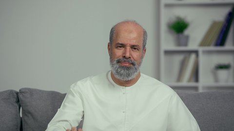 رجل كبير بالسن عربي خليجي اماراتي يرتدي الكندوره يجلس علي اريكه ويحمل شريط الدواء، ايماءه وجه منزعجه، مريض عربي اماراتي خليجي مسن يقوم بتلقي العلاج في المستشفى, الاهتمام بالصحة والالتزام بالأوقات الصحيحة لأخذ العلاج, استخدام عقار الدواء بوصفة طبية