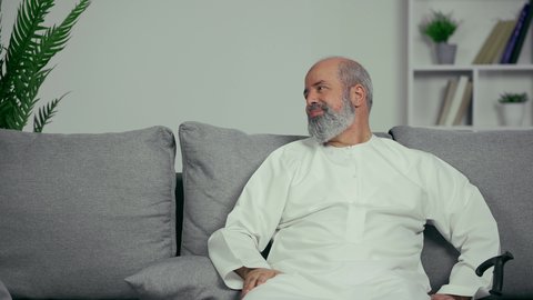 احترام كبار السن، طبيب اماراتي يصافح مريض مسن، رجل مسن يرتدي كندوره يجلس علي اريكه رماديه بجوار العكاز