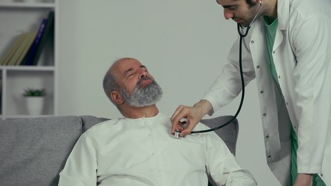 مفهوم الطب والرعاية الصحية، طبيب عربي اماراتي خليجي يرتدي المعطف الأبيض يقوم بسماع دقات القلب للتأكد من سلامة المريض، تقديم الخدمات العلاجية للمرضى بكل كفاءة، مهن ووظائف طبية، فحوصات وتشخيص نوبات القلب