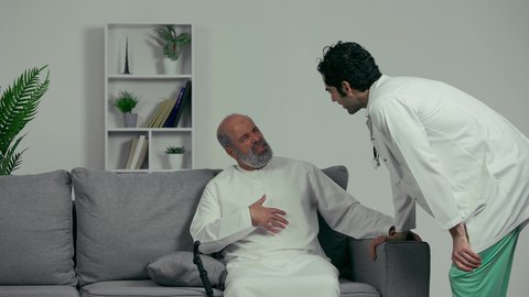 رجل مسن يشتكي من ألم البطن، آلام البطن والقولون، طبيب اماراتي يرتدي المعطف الابيض والسماعه الطبيه يقوم بالتحدث مع رجل مسن، مهن طبيه